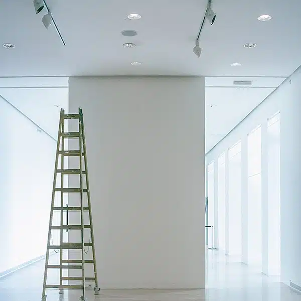 échelle devant un mur blanc dans un local vie blanc et lumineux avec un chantier d'installation de l'éclairage électrique en cours.
